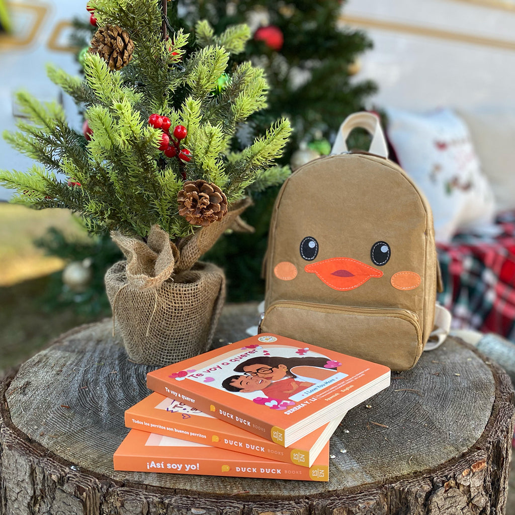 Outdoor shot of Duck Duck Backpack three kids book gift bundle in Spanish, I Love You More, All Puppies Are Good Puppies, I Am Me!